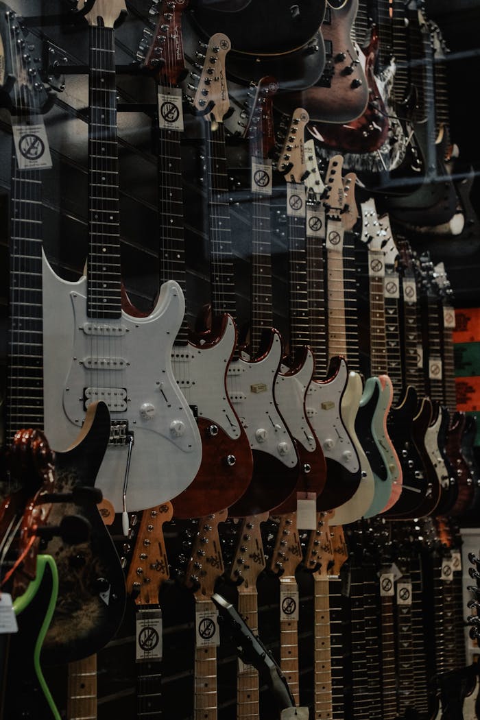 Home A vertical shot of assorted electric guitars hanging on a wall display in a music store.