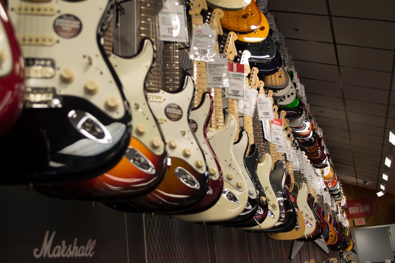 Home Row of colorful electric guitars hanging in a music store, showcasing diverse models and prices.